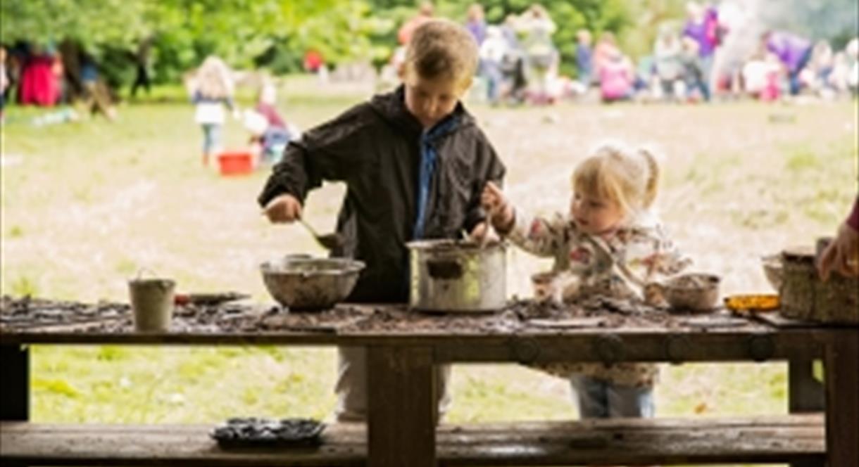 Two young children get their hands dirty in a mud kitchen at The Wolseley Centre, Staffordshire