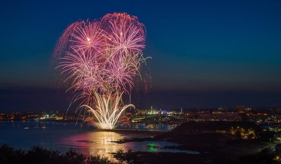 Fireworks launching from the pier at night