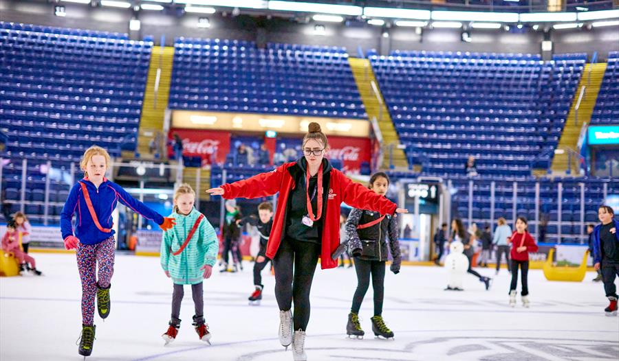 Photo of a holiday club with instructor and children on the ice