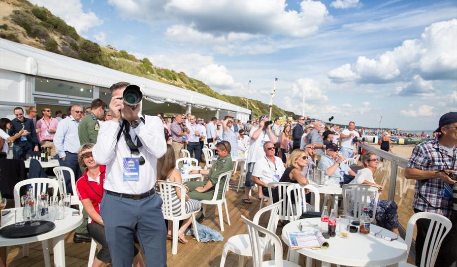 Photographer points his camera towards the skies with seated people in background