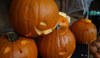 A small stack of pumpkins, carved with spooky faces.