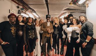 a group of musicians Soul II Soul band in costumes posing for a photo before going on stage @ Sidmouth International Jazz & Blues Festival