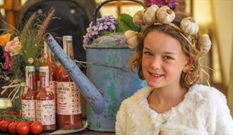 Girl with a garlic head band on standing next to local produce at the Isle of Wight Garlic Festival, what's on, event, Newchurch