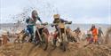 A motorbike rider has to get off his bike during a beach race as he tries to get his machine over a sand obstacle