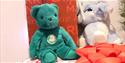 A green teddy bear and a light blue elephant sat on a present in the grotto.