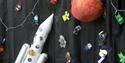 A handmade space scene with a rocket, planet and astronauts