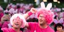 Two men in pink wigs and t-shirts smiling