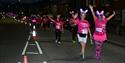 lines of people walking in the dark wearing pink t-shirts and light-up bunny ears