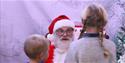 Santa is looking at a young boy and girl, who have their backs to the camera.