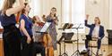 Five musicians, including a drummer and a cellist, in practice for their next performance