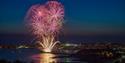 Fireworks launching from the pier at night