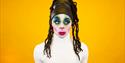 A performer dressed up against a yellow background