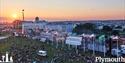 Crowd on Plymouth Hoe at sunset, with fairground rides in the background