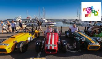 Three sports cars on Poole Quay with boats in background.