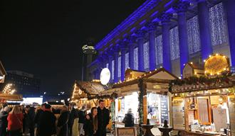 St George's Hall lit up with Christmas lights and wooden chalets decorated in Christmas lights