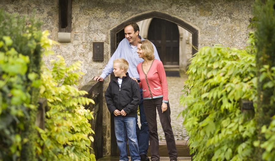 A family standing on the drawbrige outside Ightham Mote