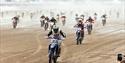 Scores of bikers throw up sea spay as they race along a beach