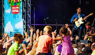 Children dancing to a singer on stage