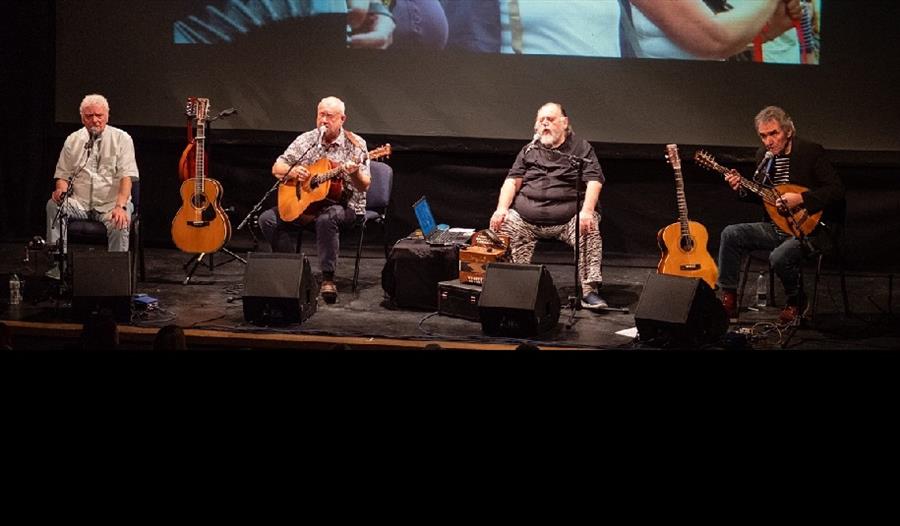 'The Pitmen Poets' performing on stage. Image of the musicians with their guitars.