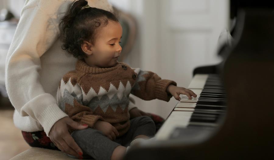 Baby sits next to a piano