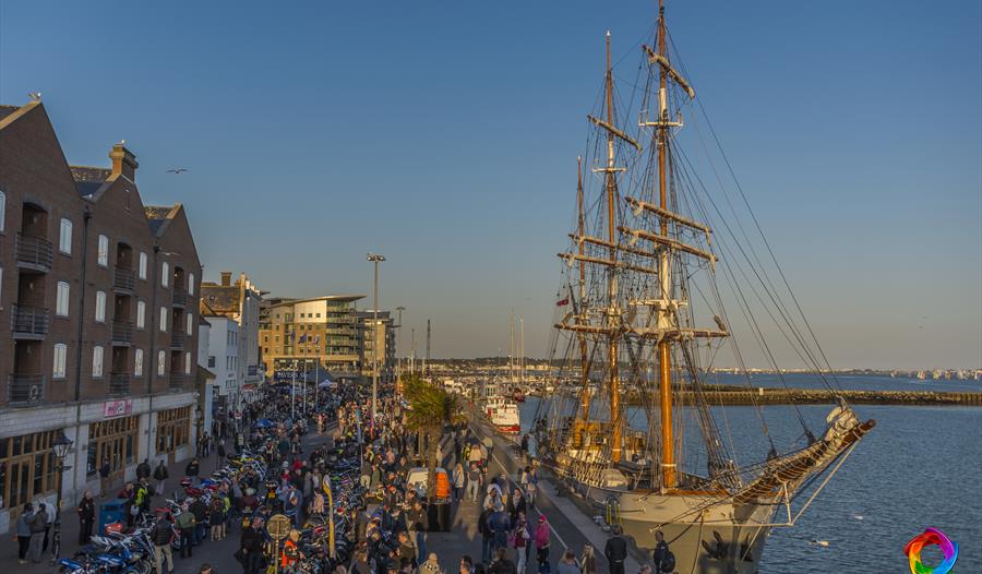 Poole Quay with crowds, motorcycles and a tall ship alongside Quay.