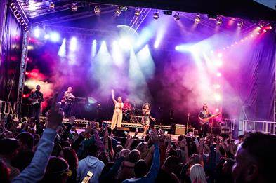 Image shows a band performing on stage in front of a big crowd