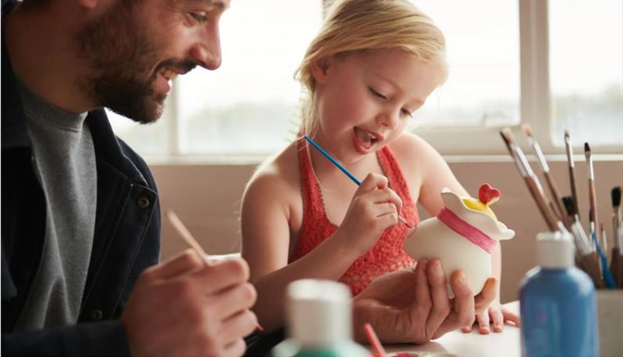 Man and child painting pottery.