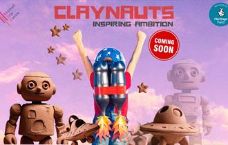 A rose-tinted sky as the background with objects made of clay such two robots, two spaceships and a person with a jetpack with flames emanating from i