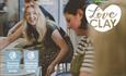 A visitor smiles at her friend as she starts off her potter's wheel in a pottery class