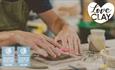 Focused in on a pair of hands cutting into clay slab on a table