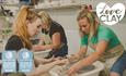 Two ladies throwing a pot at LoveClay Ceramics Centre, infront of them is a studio instructor helping one of the ladies.