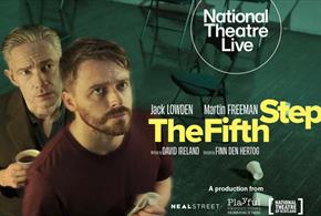 An Image of a room with some chairs which has a blue tint and two men (both do not have the blue tint) one stood behind the other man, both are lookin