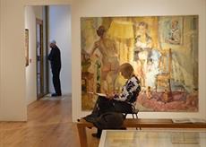 An adult drawing in front of a painting