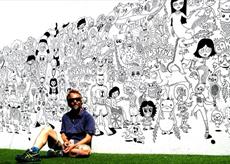 The artist sitting in front of a black and white mural in a comic style