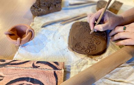 Someone impresses floral patterns into clay