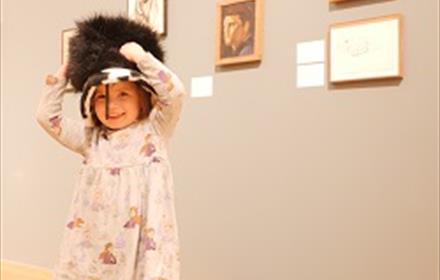 A child smiling wearing a large hat