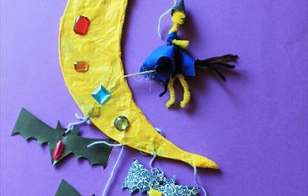 A yellow paper moon with bats hanging from it