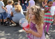 A child blowing bubbles through a bubble device made from recycled materials.