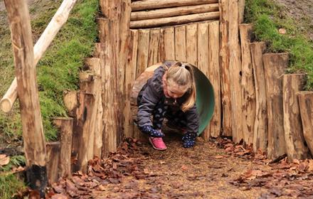 A girl crawls through tunnel, enjoying the new play area at Polesden Lacey