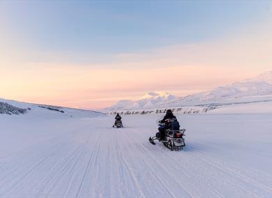 People driving snowmobiles