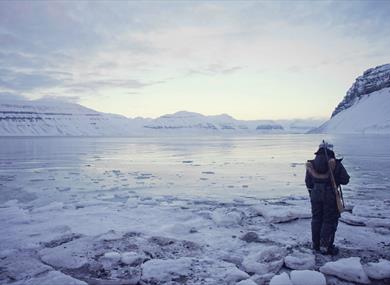 Guide standing by the ice with a rifle