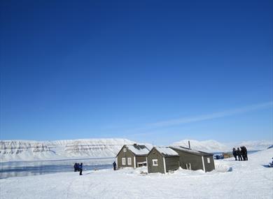 The trapper's cabin in Fredheim is well situated in the snow-covered terrain. In the background you can see a fjord and a mountian formation.