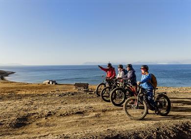 A guide and guests on bikes taking a break to look at the nature around them