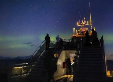 People on a boat watching northern lights 