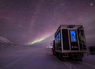 Northern Lights shining in the skies above a snowcat