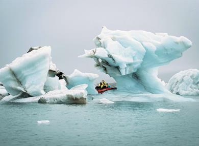 A boat in between pieces of ice floating at sea
