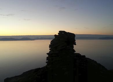The cairn on top of Fuglefjella in sillhouette against the fjord Isfjorden in dusk light conditions