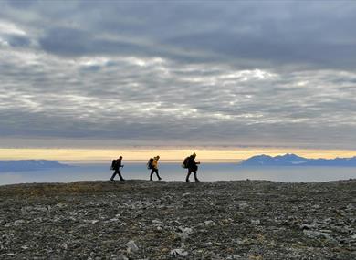 Three persons hiking along the shore 