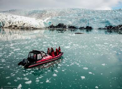 A boat with guests on board sailing in front of a glacier