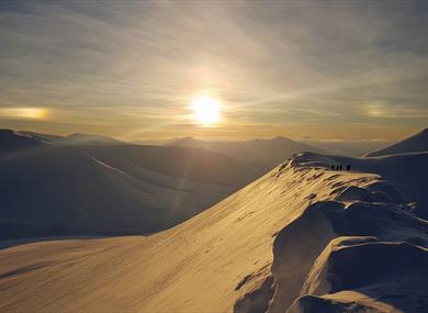 The sun shines on the snow-covered mountain top with beautiful snow-covered mountains in the back ground